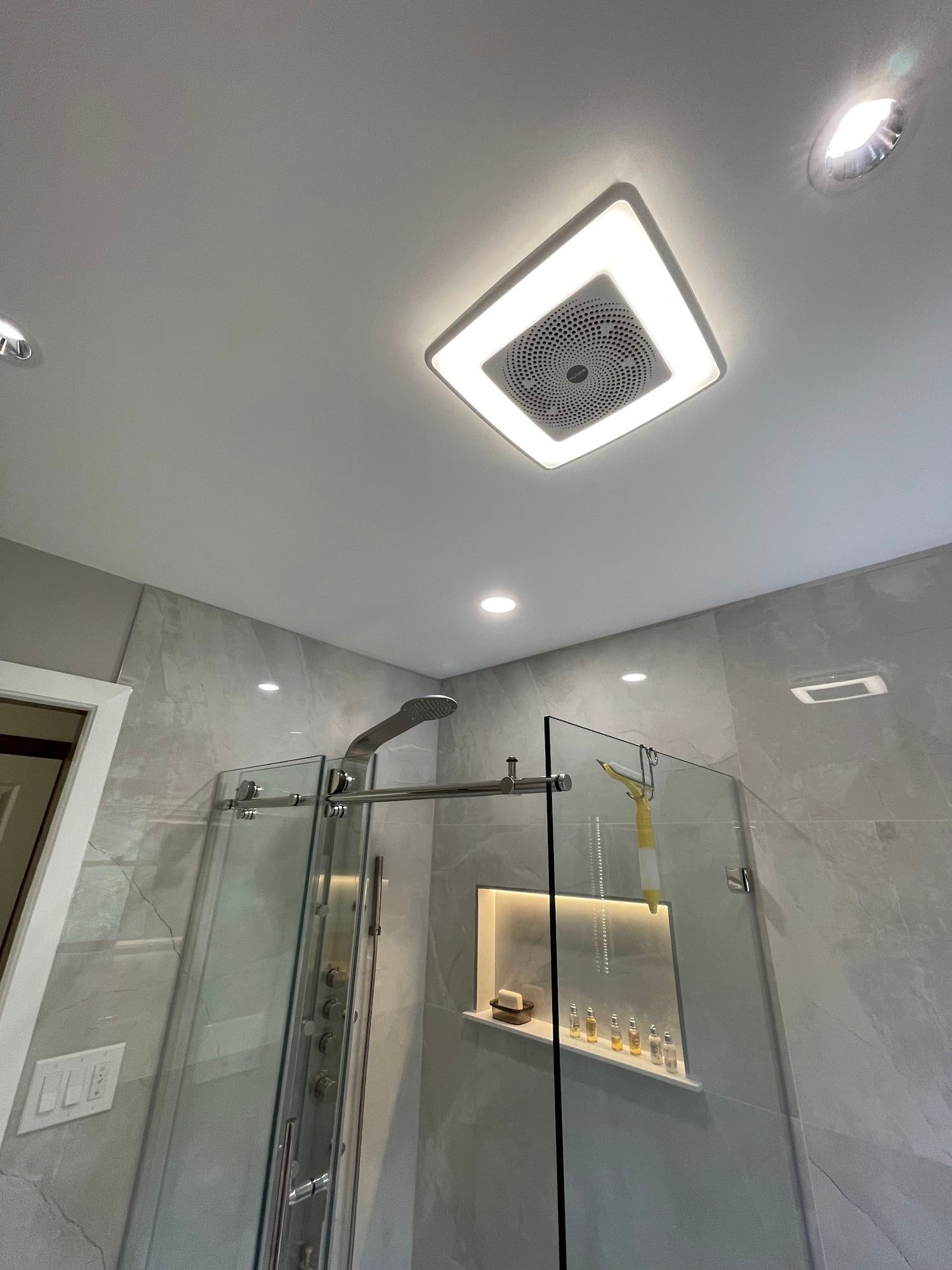 Ceiling light and shower glass in a tiled bathroom