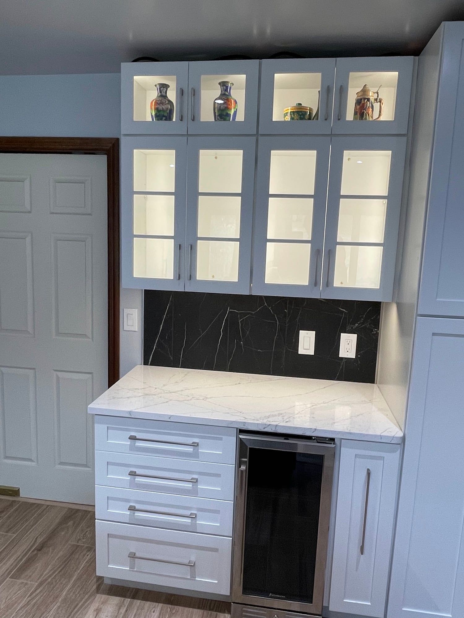 Lit glass-front display cabinets over a beverage station