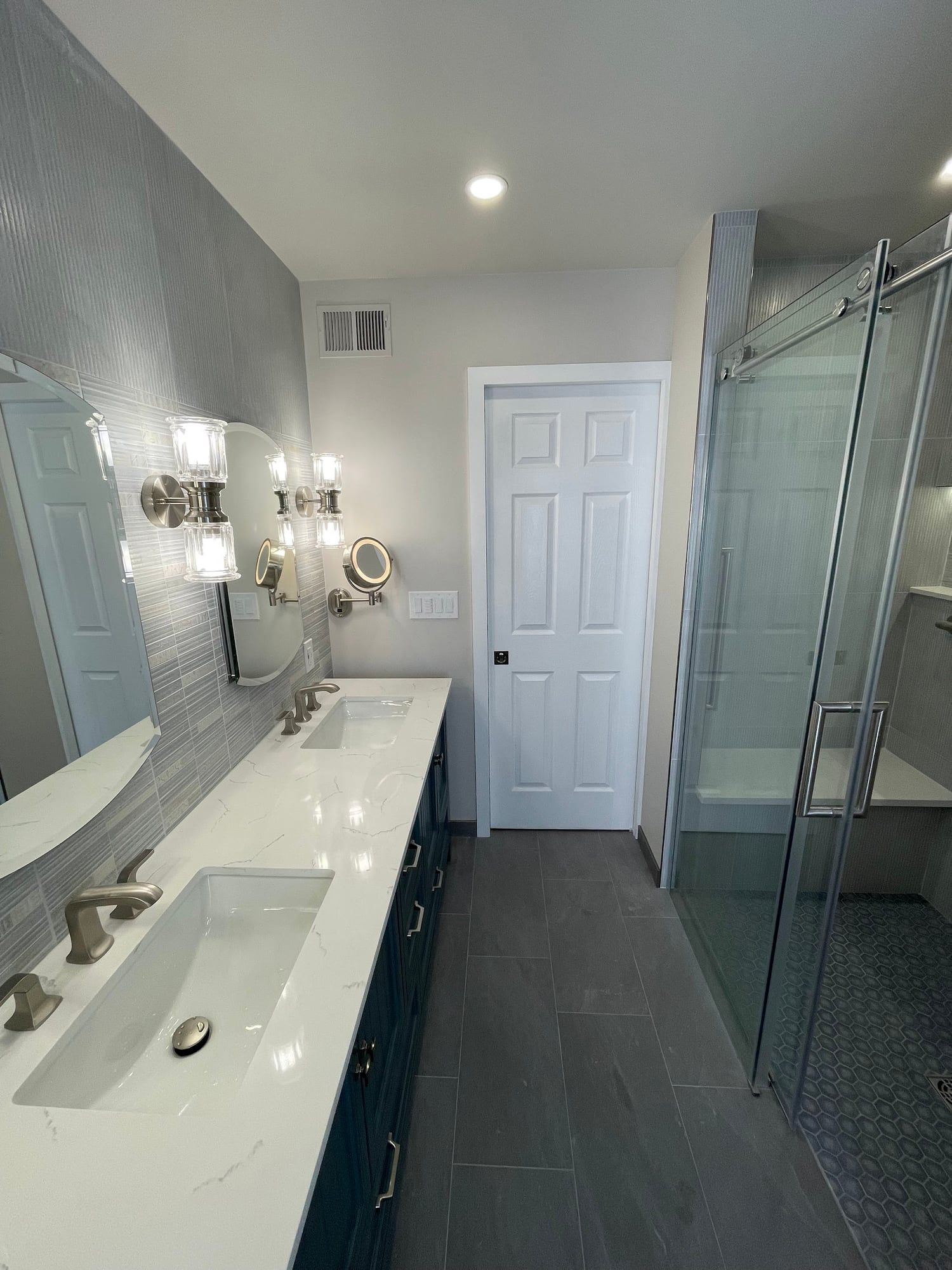 Vanity run and glass shower seen toward the door