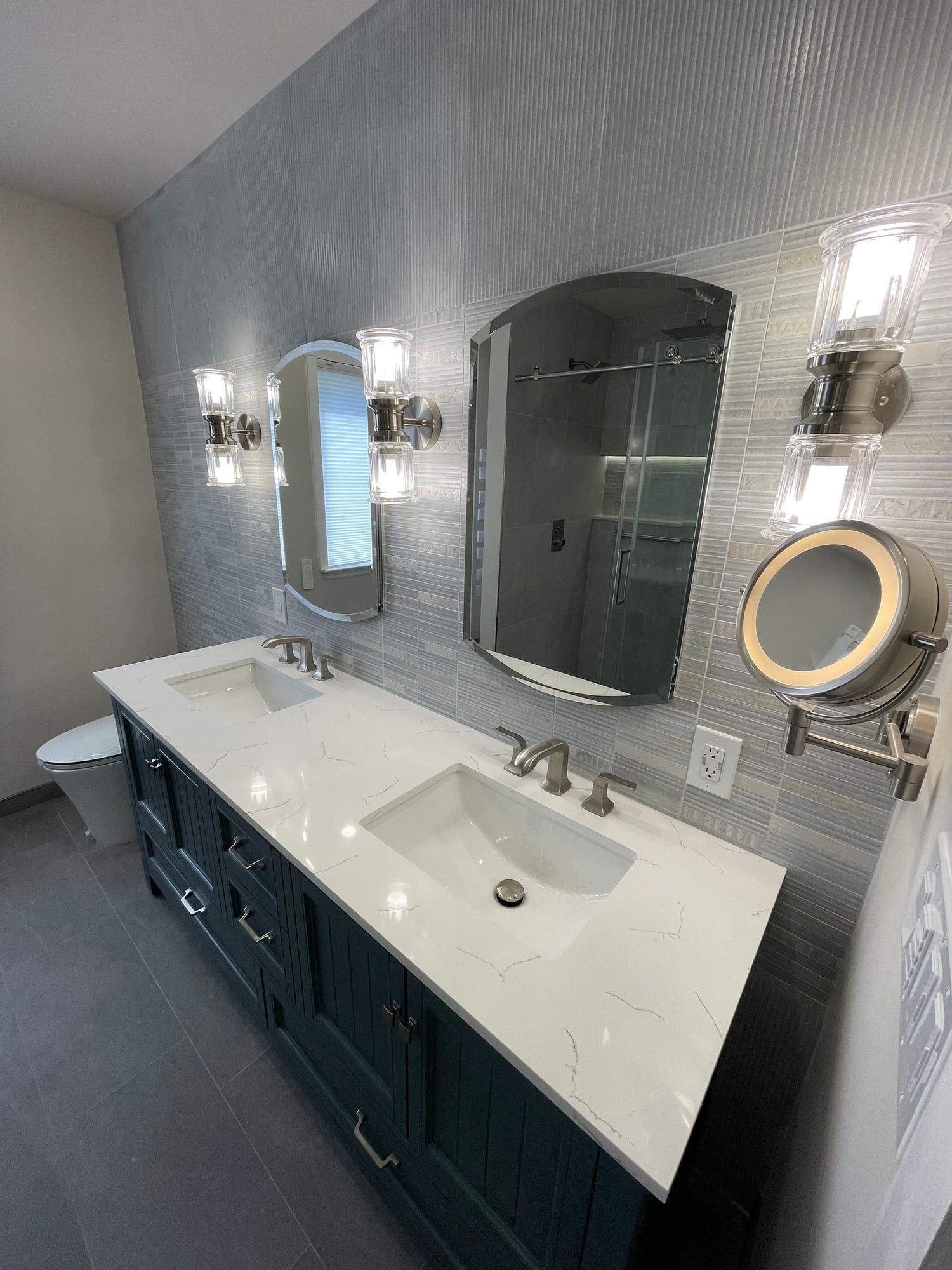Navy double vanity with quartz top, arched mirrors and crystal sconces