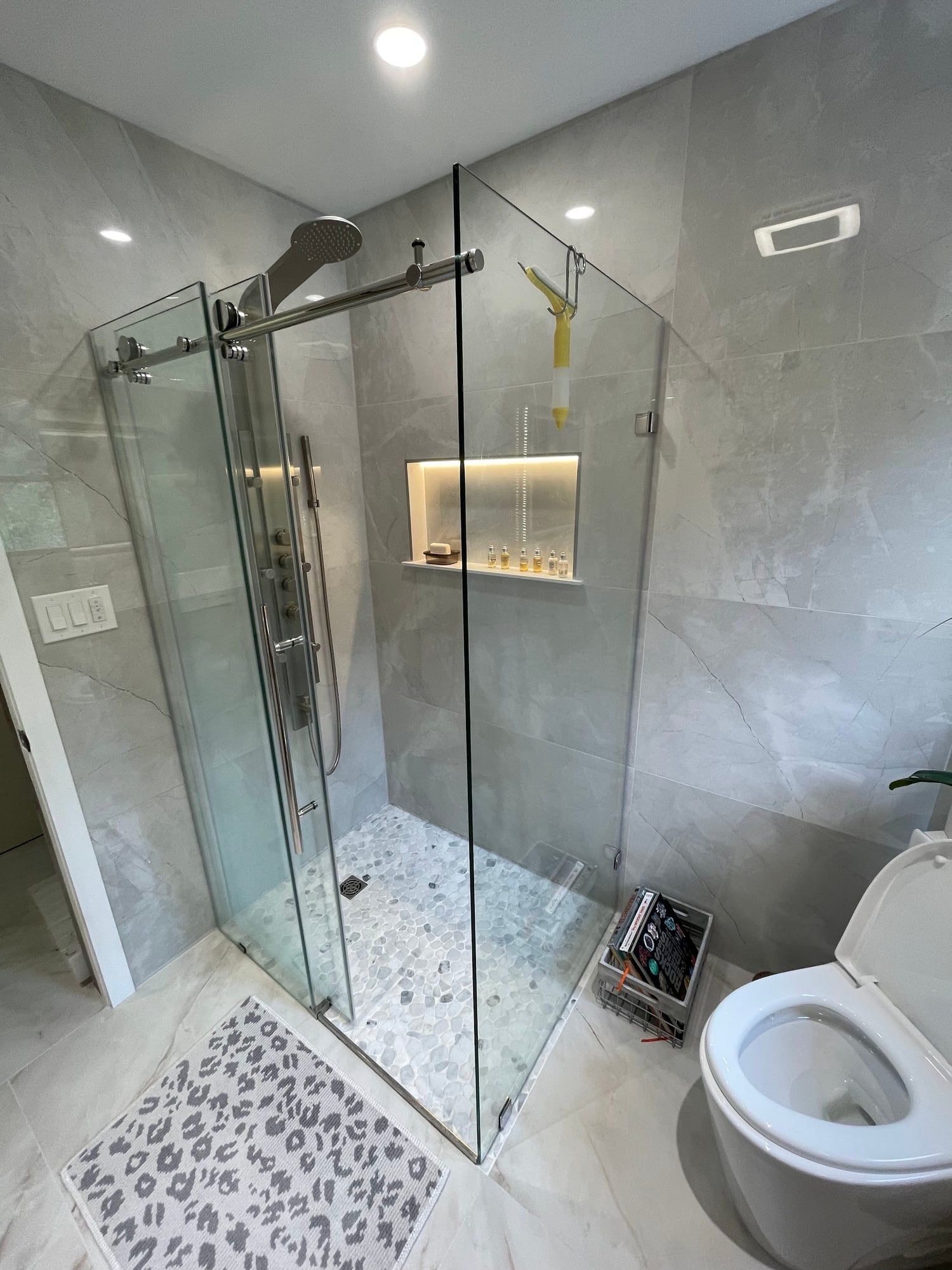 Corner glass shower enclosure with a lit niche