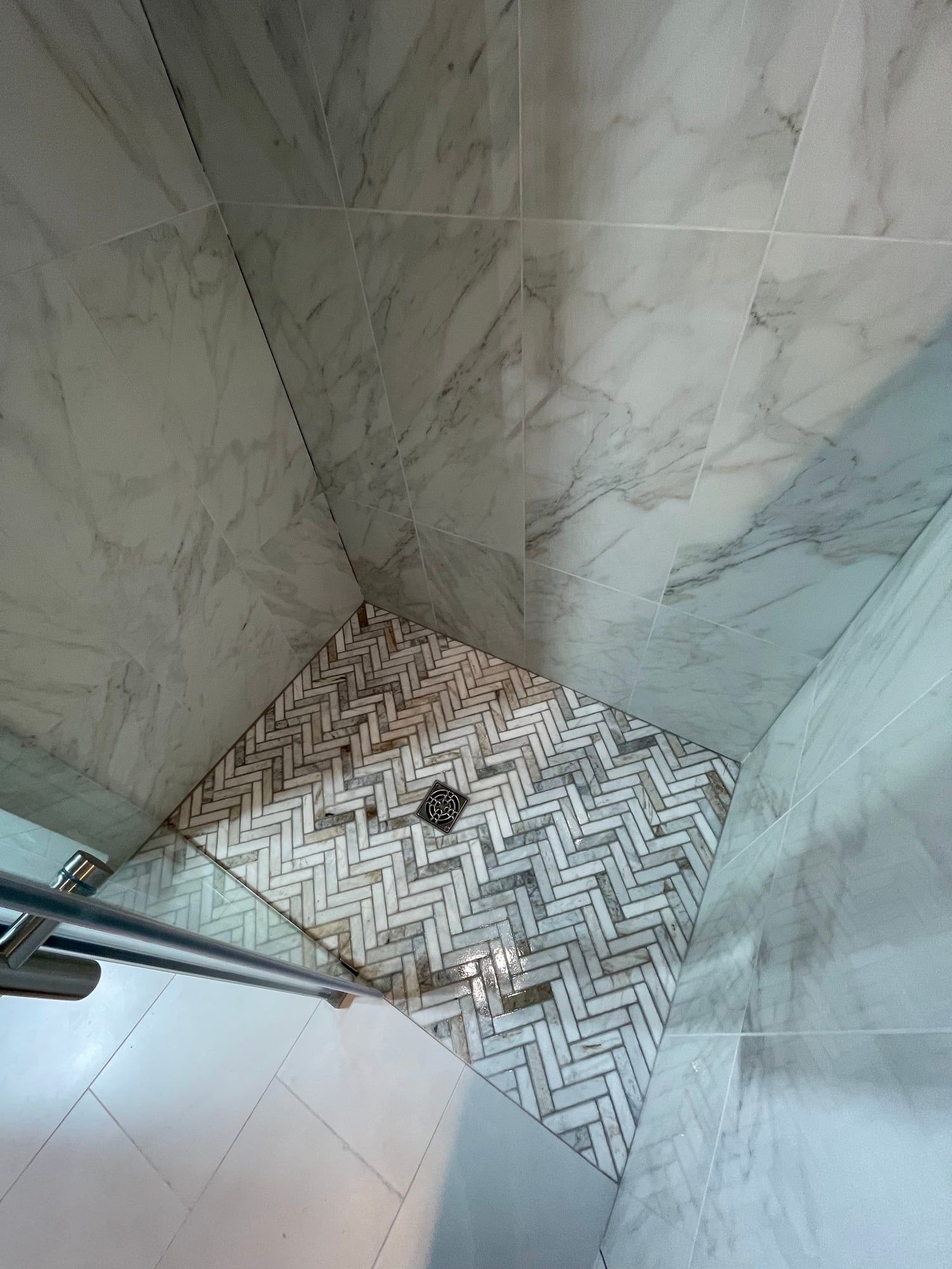 Herringbone mosaic shower floor meeting large-format wall tile