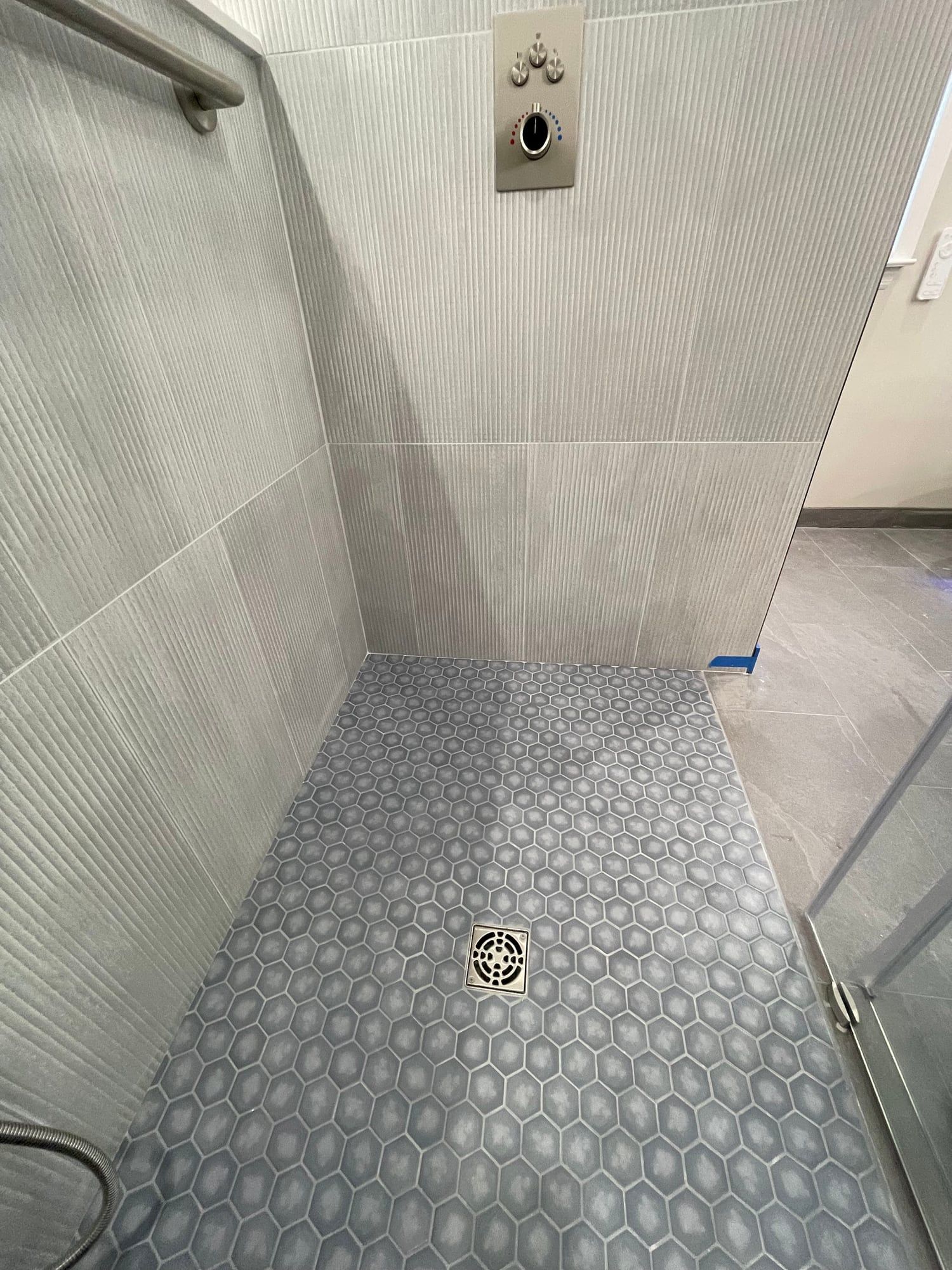 Blue hex mosaic shower floor around a square drain