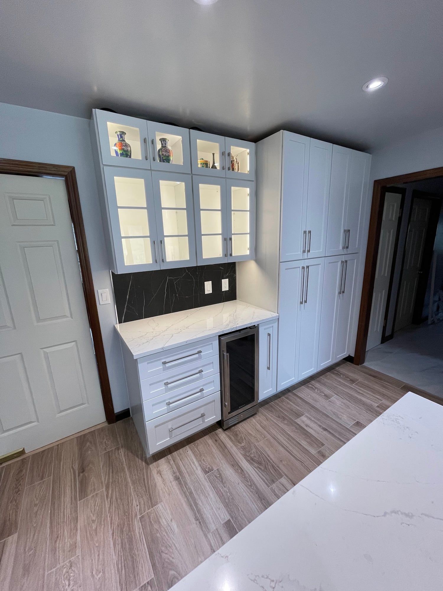Glass-front hutch and tall cabinets beside a doorway