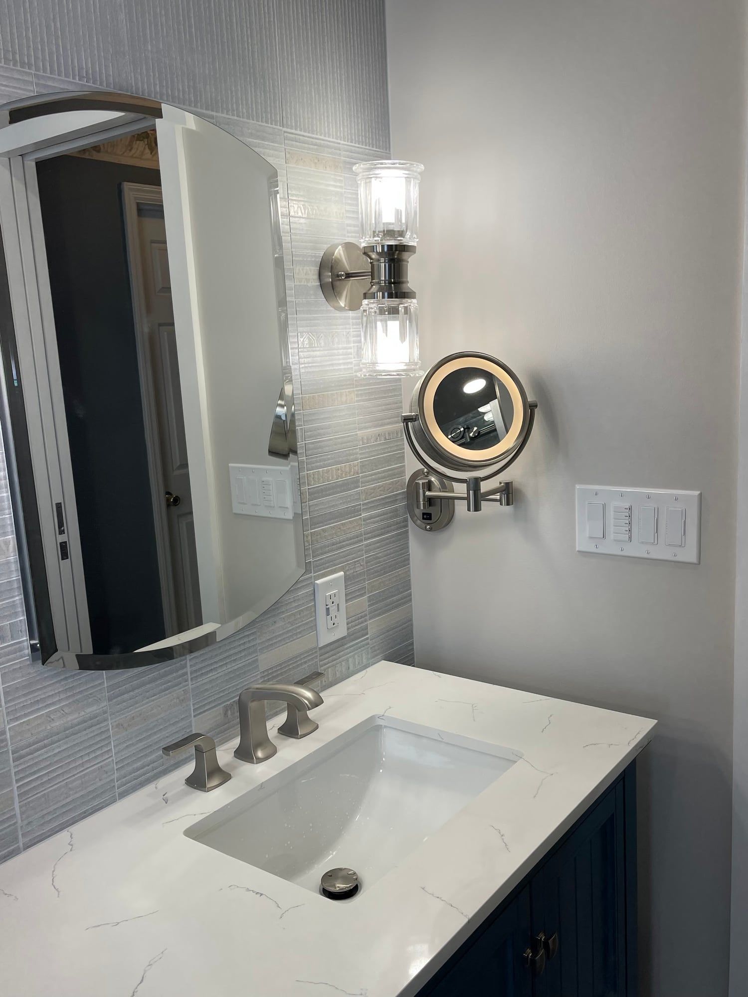 Arched mirror, crystal sconce and lit magnifying mirror over the vanity