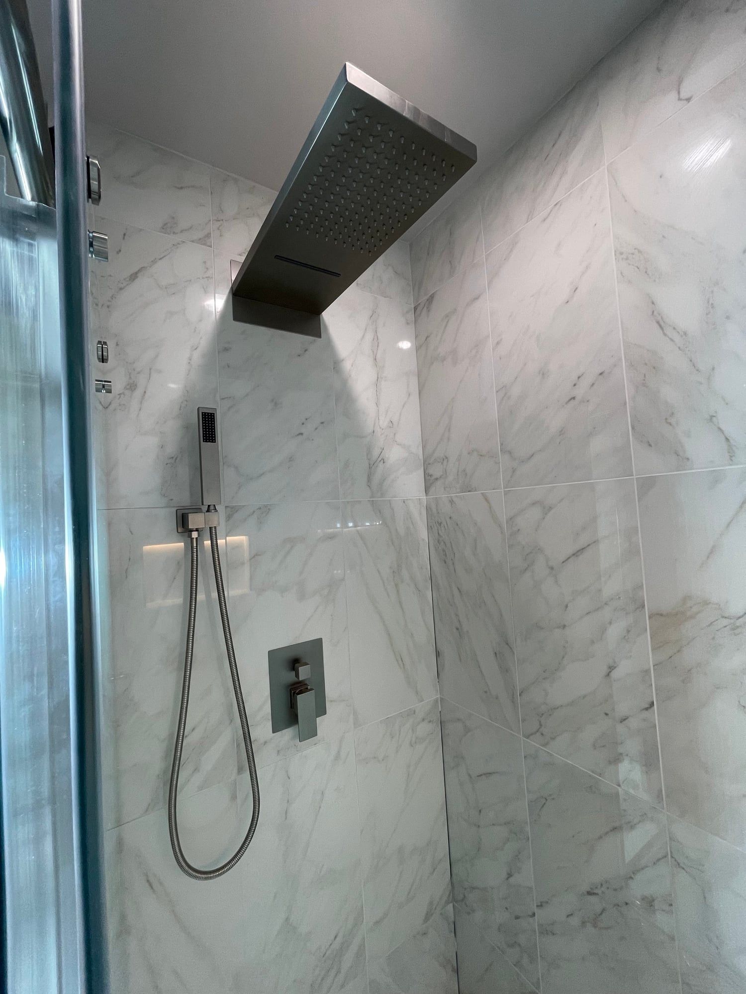 Rain head and hand shower in marble-look tile