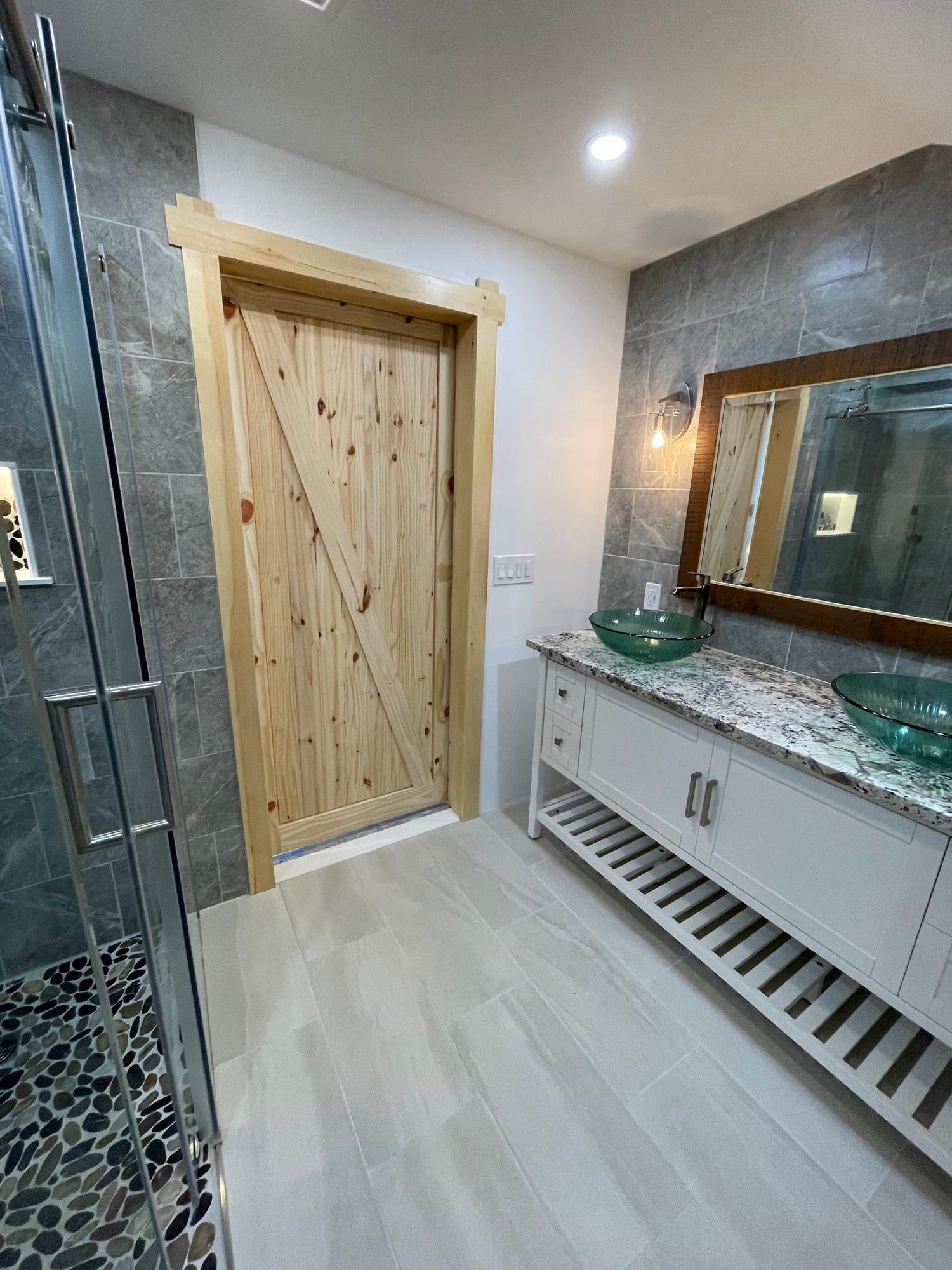 Guest bath seen past the shower glass toward the plank door