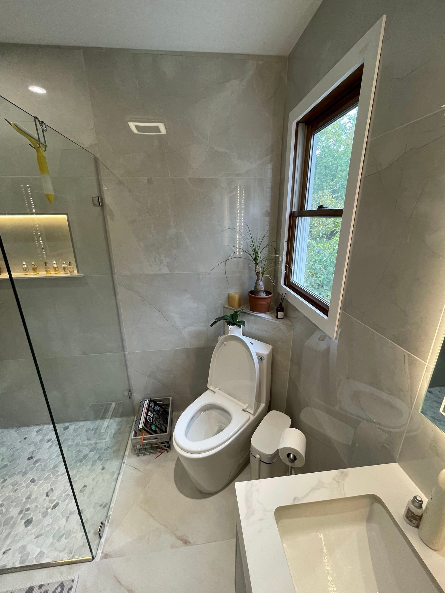 Bathroom with a glass shower, window and wall-hung toilet