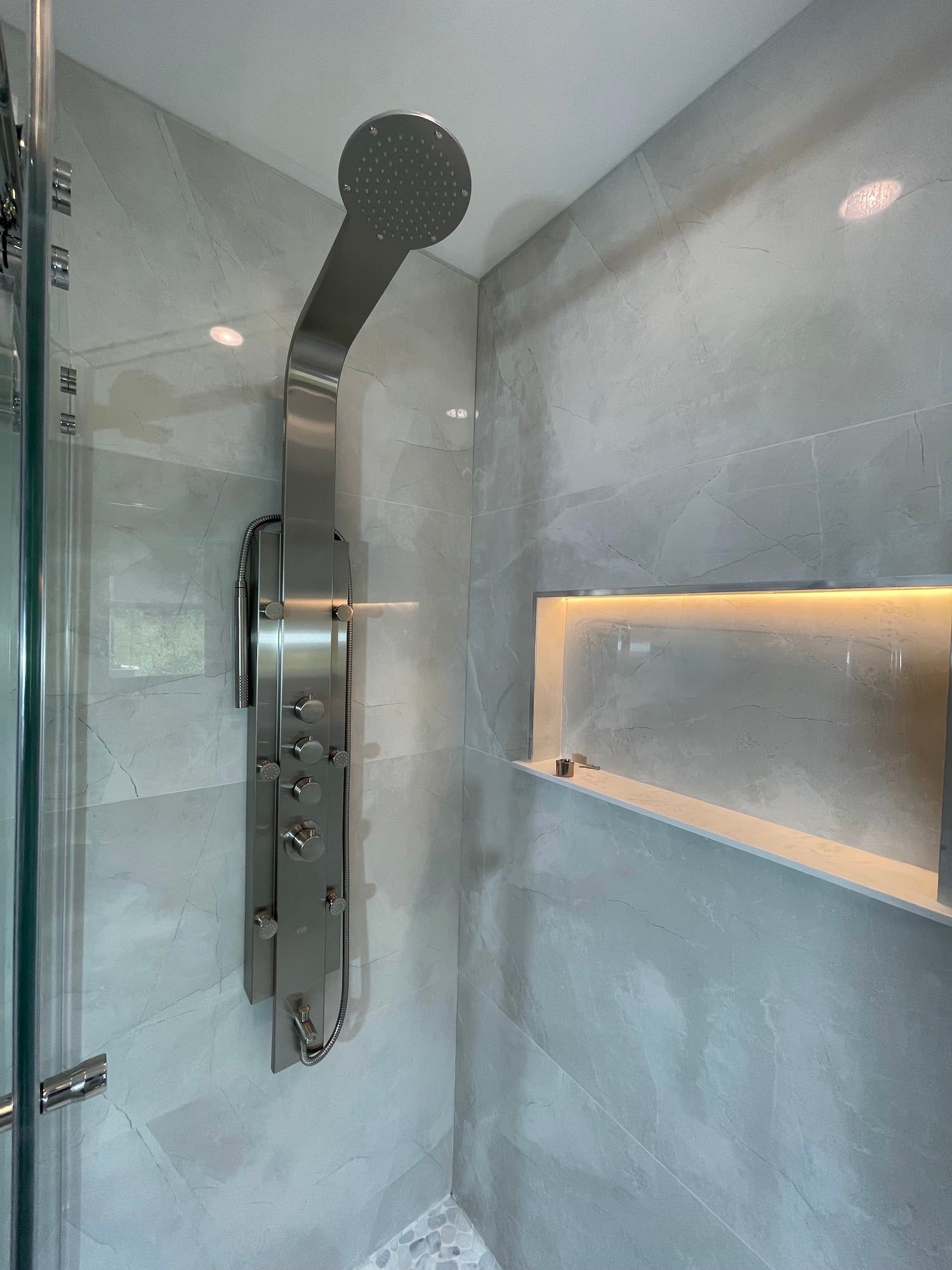 Stainless shower panel beside a long lit niche