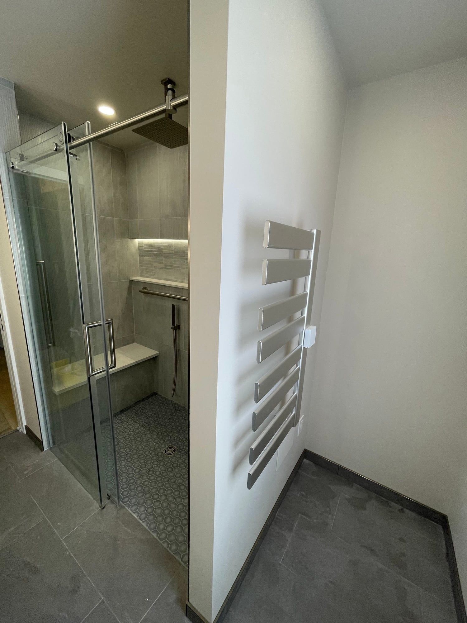 Wall-mounted towel warmer beside the glass shower
