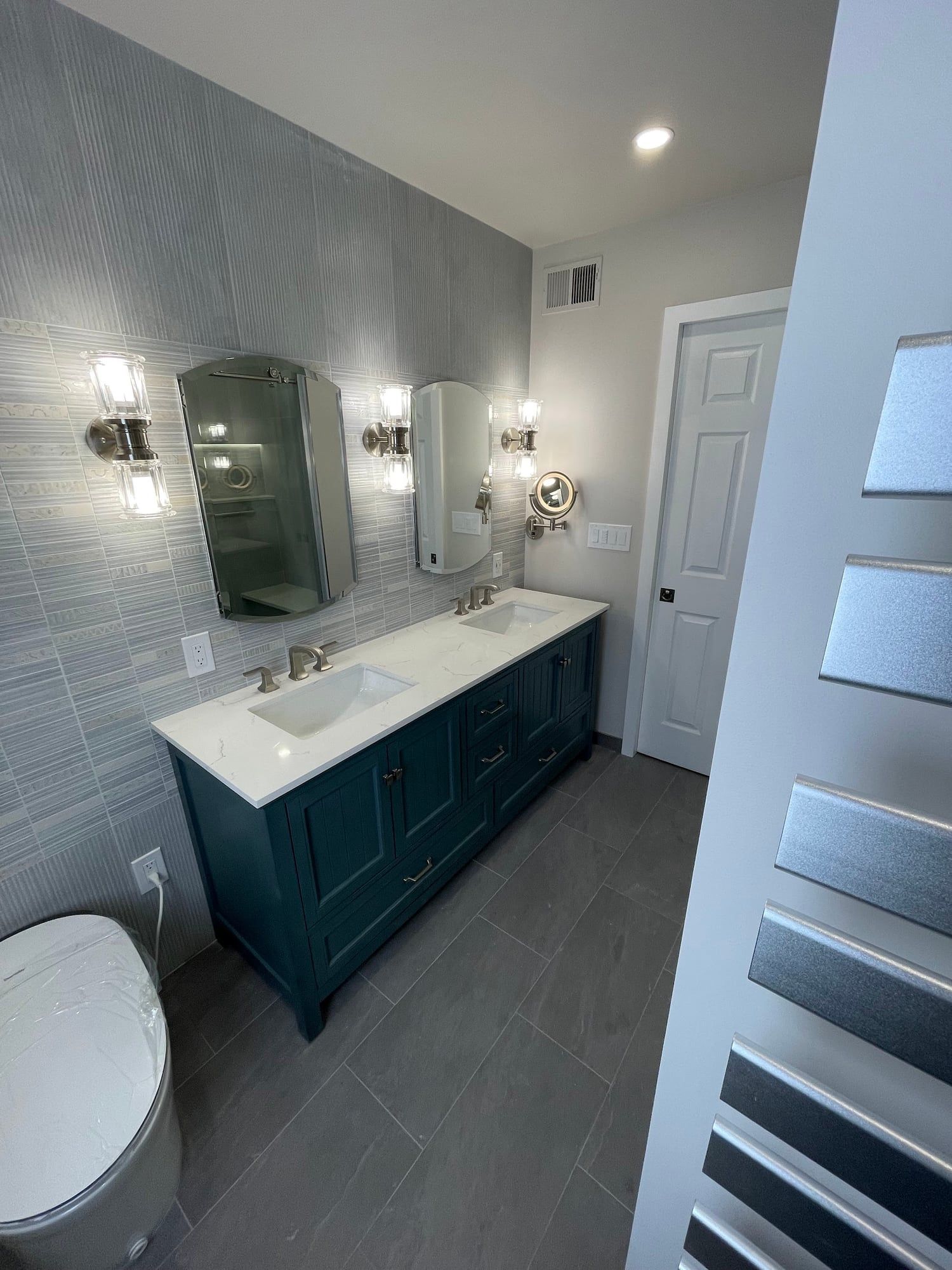 Navy vanity with two sinks and a wall of textured tile