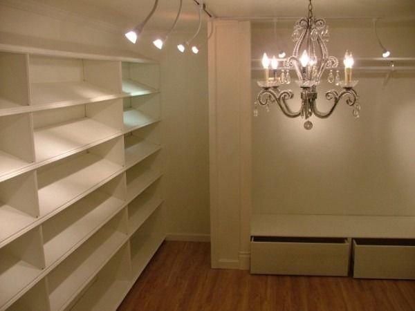 Wall of built-in white shelving with drawers under a crystal chandelier