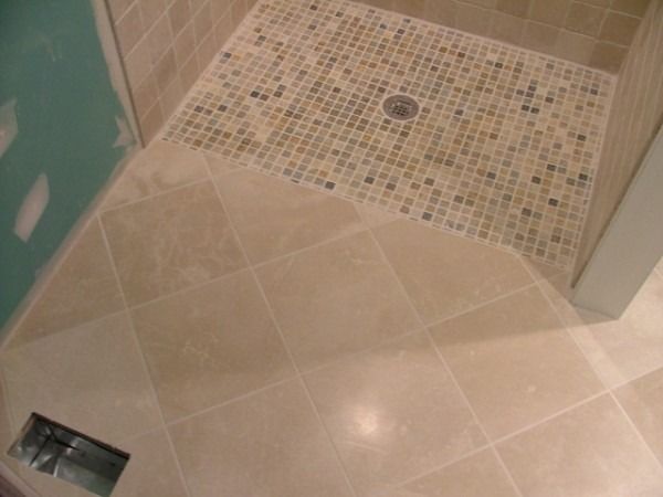 Large stone-look floor tile meeting a mosaic shower floor