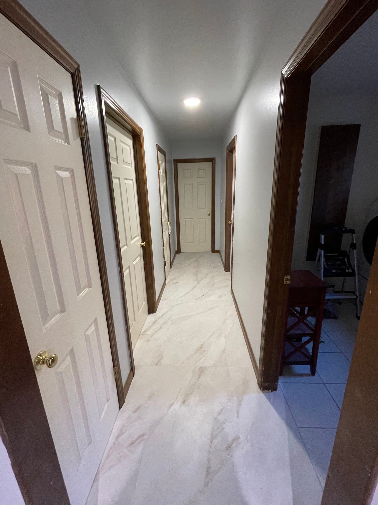 Hallway with marble-look tile floor and white doors