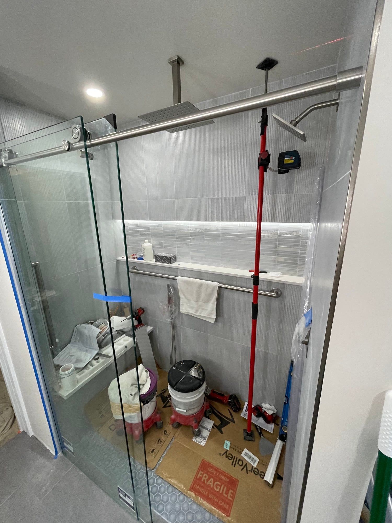 Lit niche and shower glass during installation, with a laser on the wall