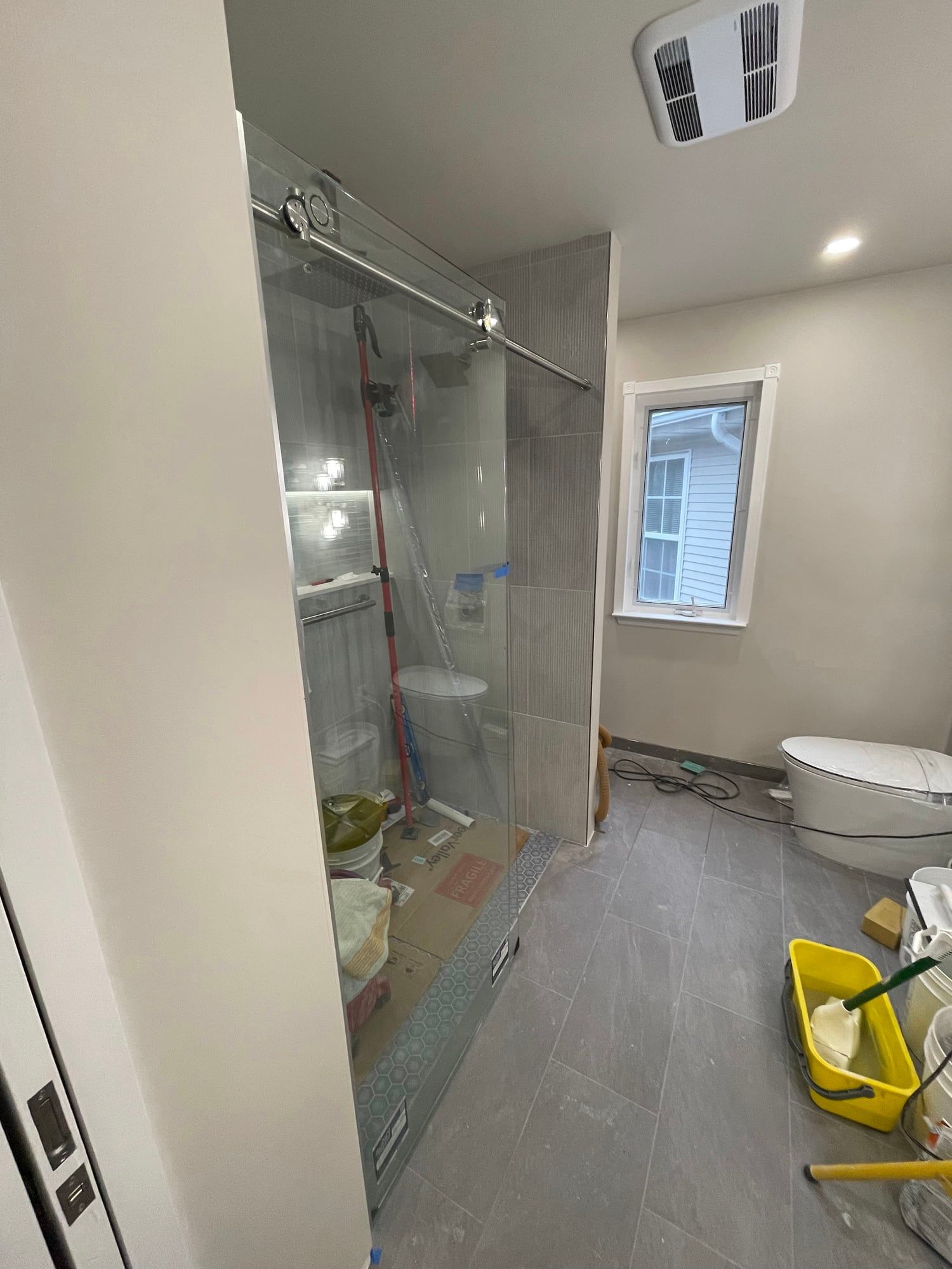 The bathroom mid-installation with tile on the walls and tools on the floor